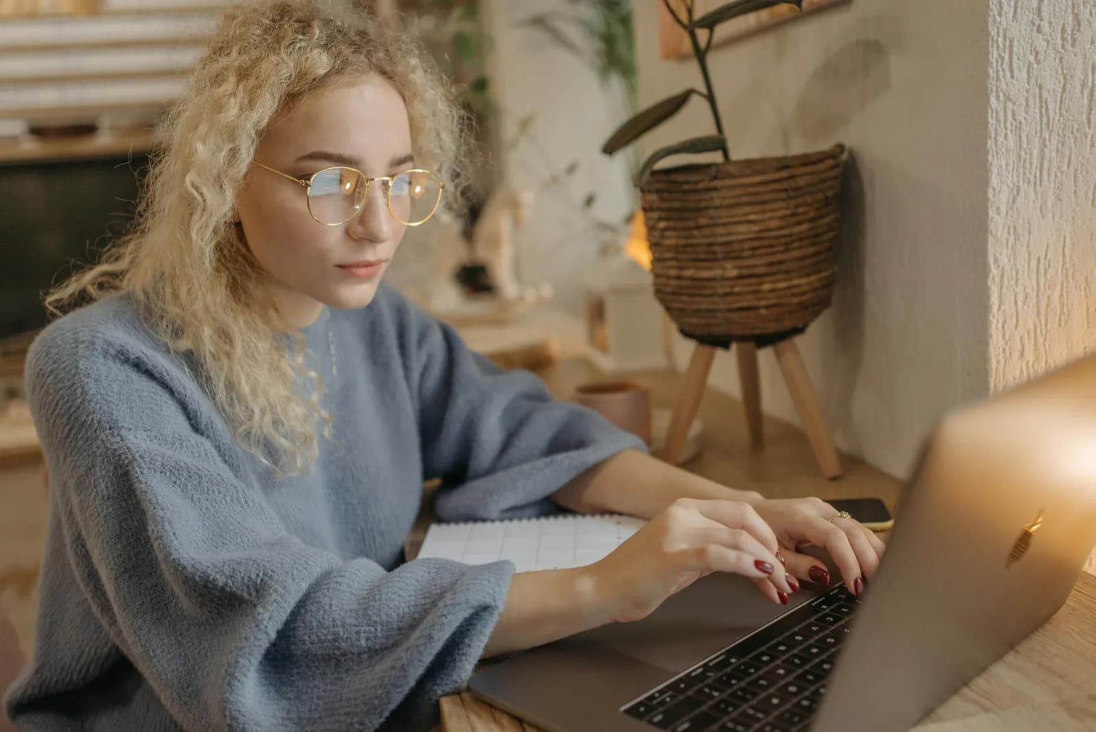 Kvinne ved hjemmekontor fordypet i laptop med dokumenter på skrivebordet, rolig og konsentrert