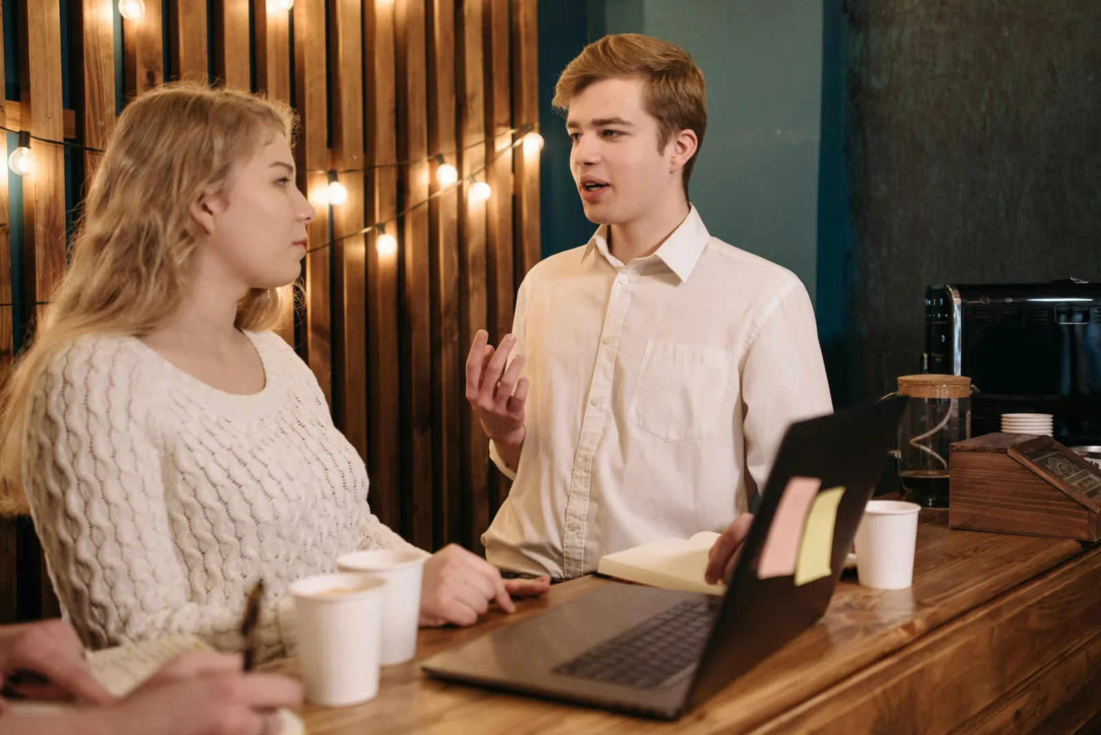 To personer ved et trebord med dokumenter og laptop, i en saklig og konstruktiv samtale om papirer